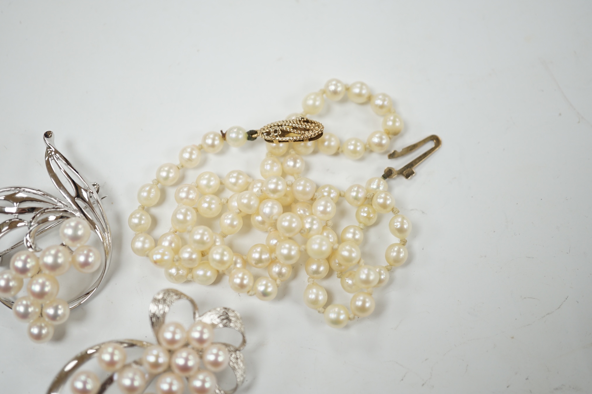A Mikimoto white metal and cultured pearl cluster set spray brooch, 41mm, one other white metal and cultured pearl cluster set spray brooch, stamped 'silver' and a single strand cultured pearl necklace with a 9ct gold cl